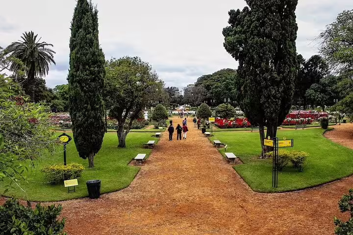 Pathway through Buenos Aires Botanical Garden with flowerbeds and tall trees, stop on full day city tour