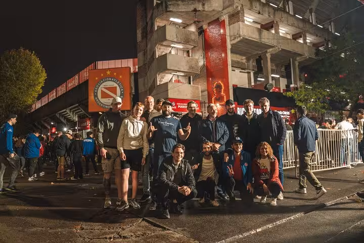 Group of travelers outside an Argentine stadium at night on Buenos Aires local soccer matchday tour