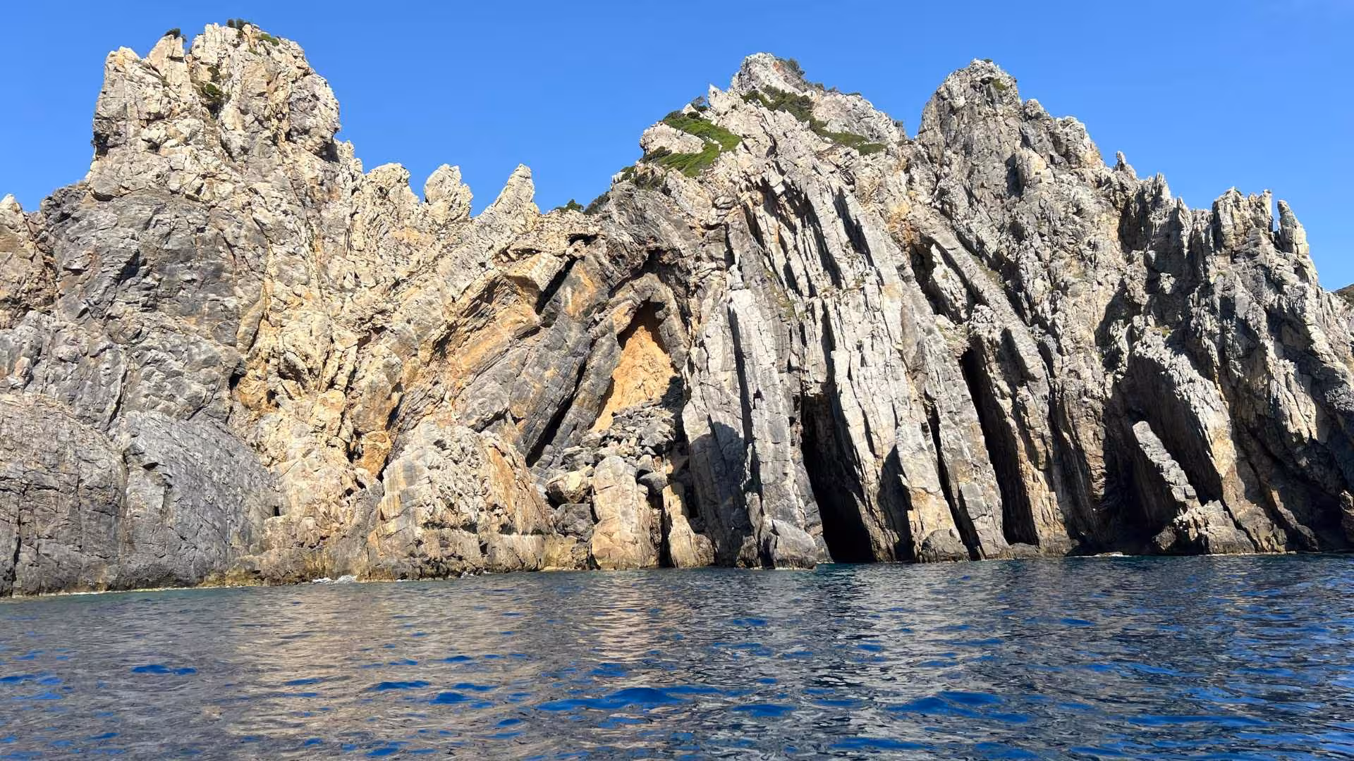Majestic rocky cliffs rise above the clear blue waters on the Buggerru dinghy tour to Pan di Zucchero.