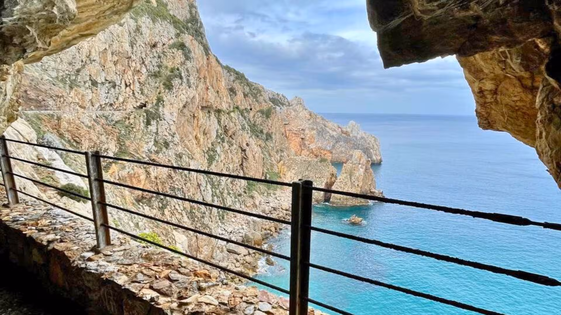 Scenic coastal view from Galleria Henry tunnel in Buggerru, revealing stunning cliffs and turquoise waters.