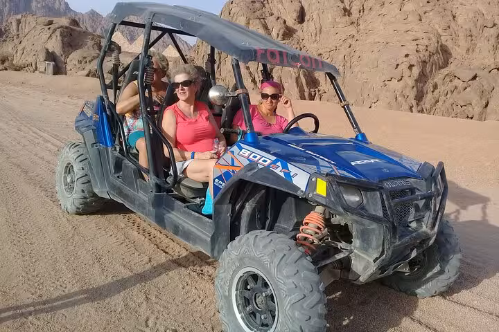 Friends riding a blue off-road buggy on a Sharm El Sheikh desert safari, driving through Sinai canyon trails