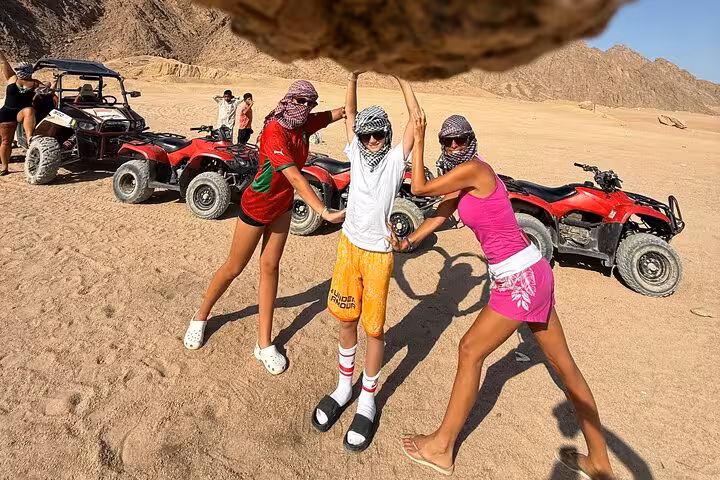 Friends pose by quad bikes on Buggy Safari Sharm El Sheikh desert tour with Sinai mountains backdrop