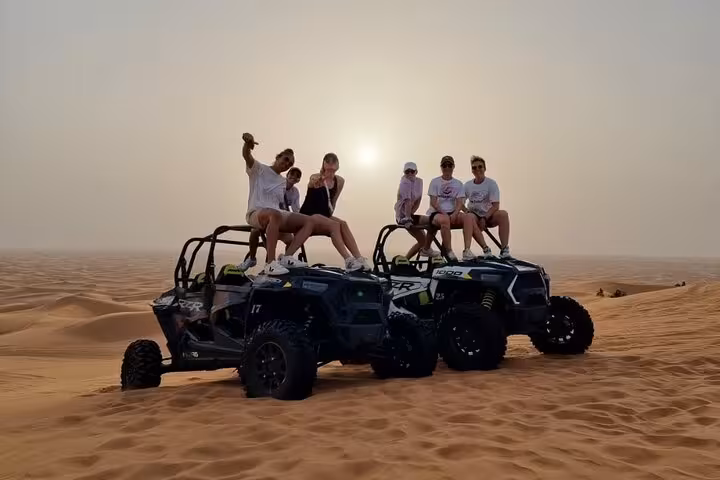 Friends sitting on dune buggies at sunset in Sharm El Sheikh desert, Buggy Safari tour with sand dunes views