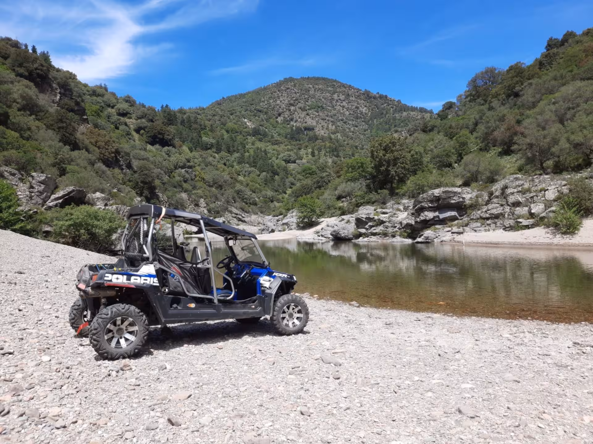 A buggy parked by a serene riverbank surrounded by lush greenery on the Gennargentu tour from Aritzo.