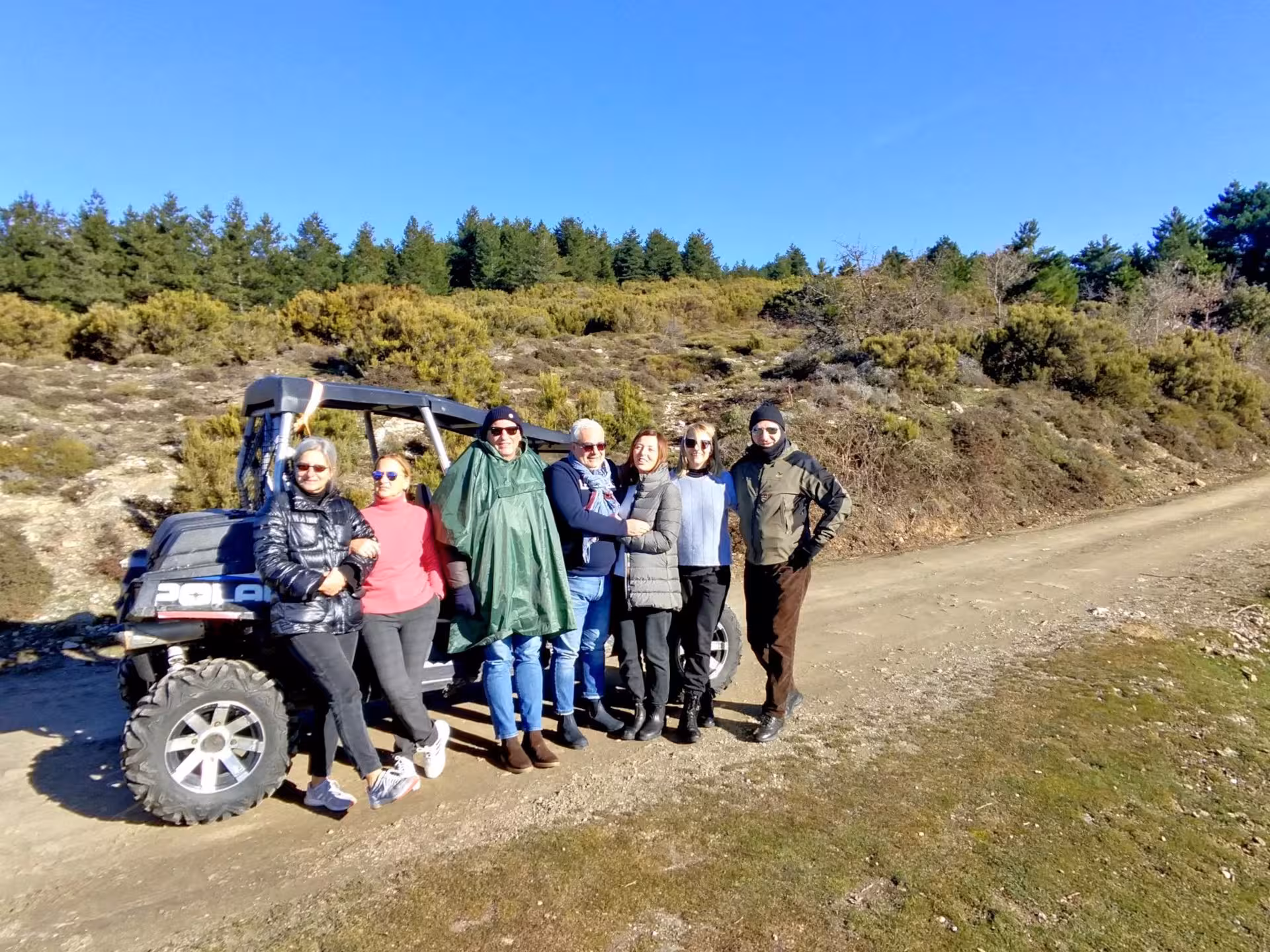 Group of tourists posing with a buggy on a sunny hillside in Gennargentu, Sardinia during an adventure tour.