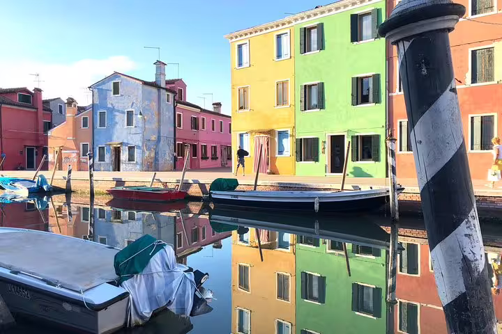 Colorful Burano canal scene with vibrant houses reflecting in the water, capturing the essence of Venice's charm.