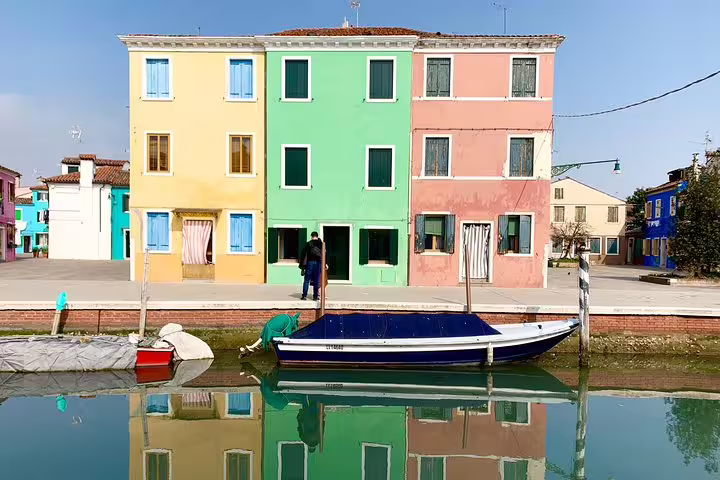 Colorful Burano canal houses reflected in water beside a moored boat on a private Murano & Burano tour
