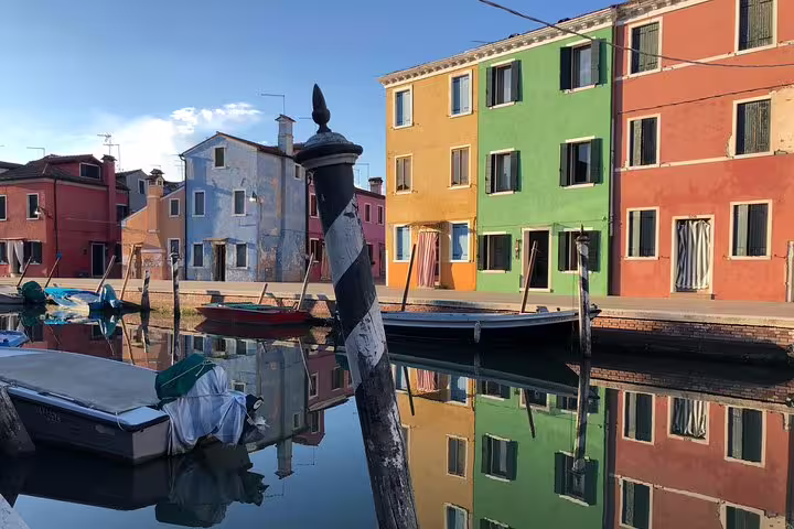 Sunset view of Burano's colorful facades and calm canal, highlighting a serene Grand Canal Boat Private Tour.