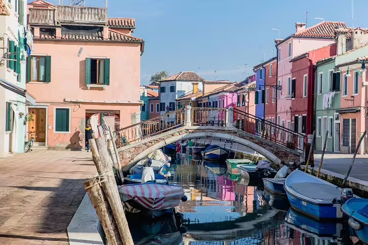Charming canal scene in Burano with colorful houses and boats, perfect for a peaceful stroll and sightseeing.