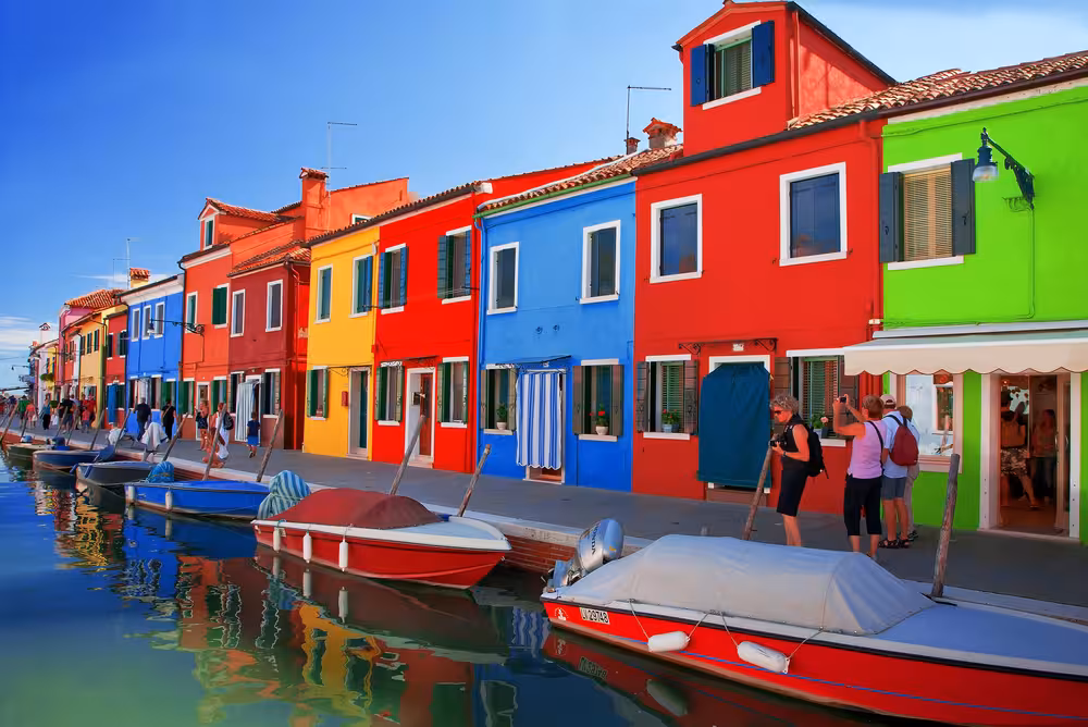 Colorful houses and small boats line the canal in Burano, a must-visit on the Venice Lagoon tour.