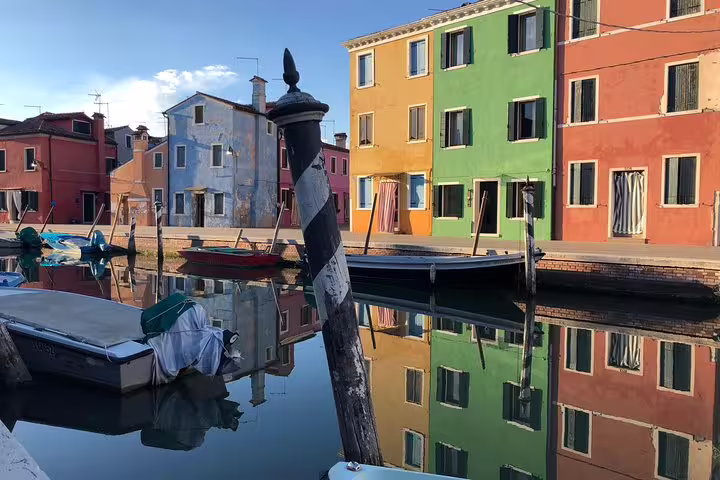 Colorful houses reflecting on the canal in Burano, a highlight of the Private LimoBoat Tour experience.