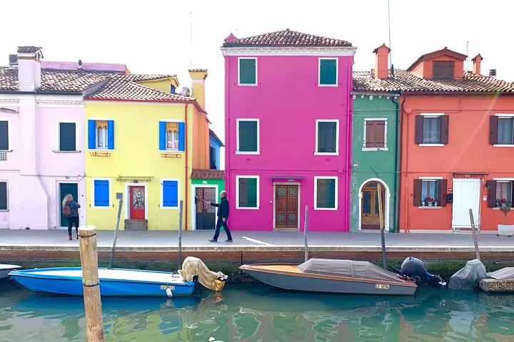 Colorful facades of Burano's charming houses reflecting in the canal, a vibrant highlight of Venice's beauty.