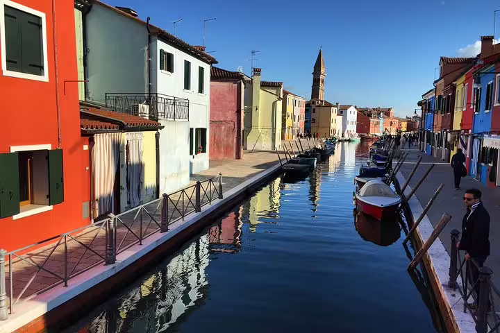 Burano canal with colorful houses and moored boats, stop on private Grand Canal tour to Murano Burano