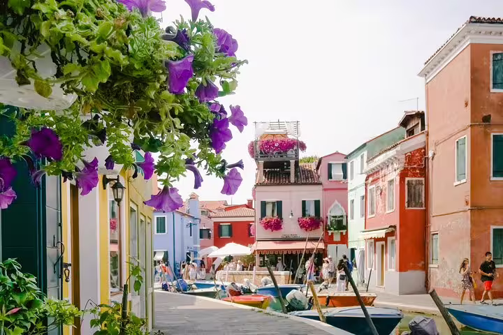 Picturesque Burano canal with vibrant flowers and colorful houses, showcasing the beauty of the Grand Canal tour.
