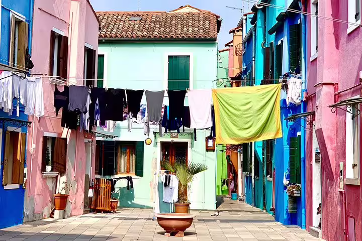Colorful houses with laundry hanging in Burano, seen on the Murano and Burano shared water taxi tour.