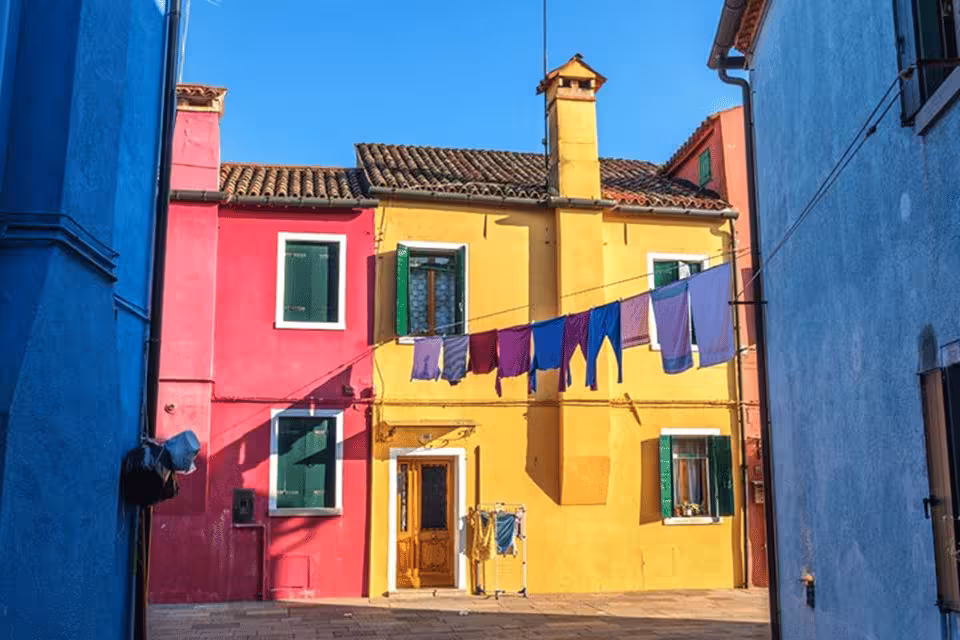 Vibrant Burano houses with colorful facades and laundry hanging, highlighting Venetian island charm on guided tour.