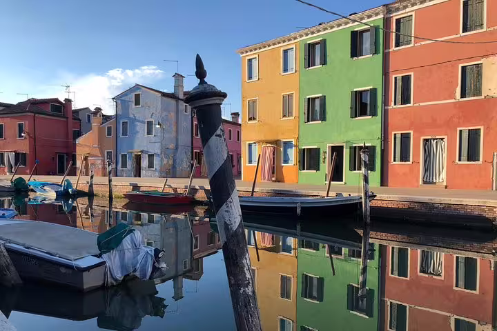 Bright Burano houses reflected in canal on Venice private Grand Canal boat tour with Murano and Burano stop