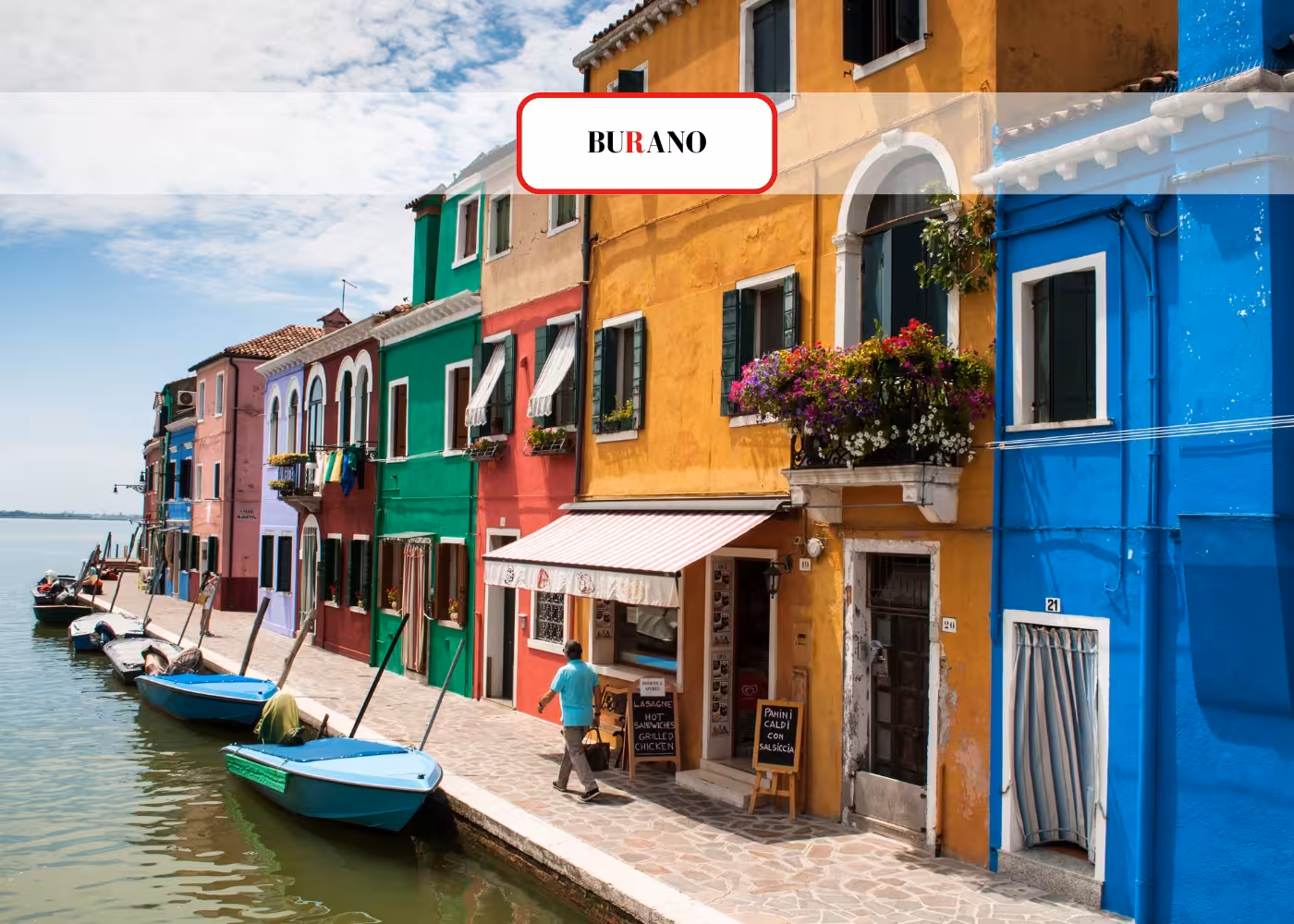 Vibrant Burano houses lining a canal with boats, part of the Venice Islands Guided Cruise experience.