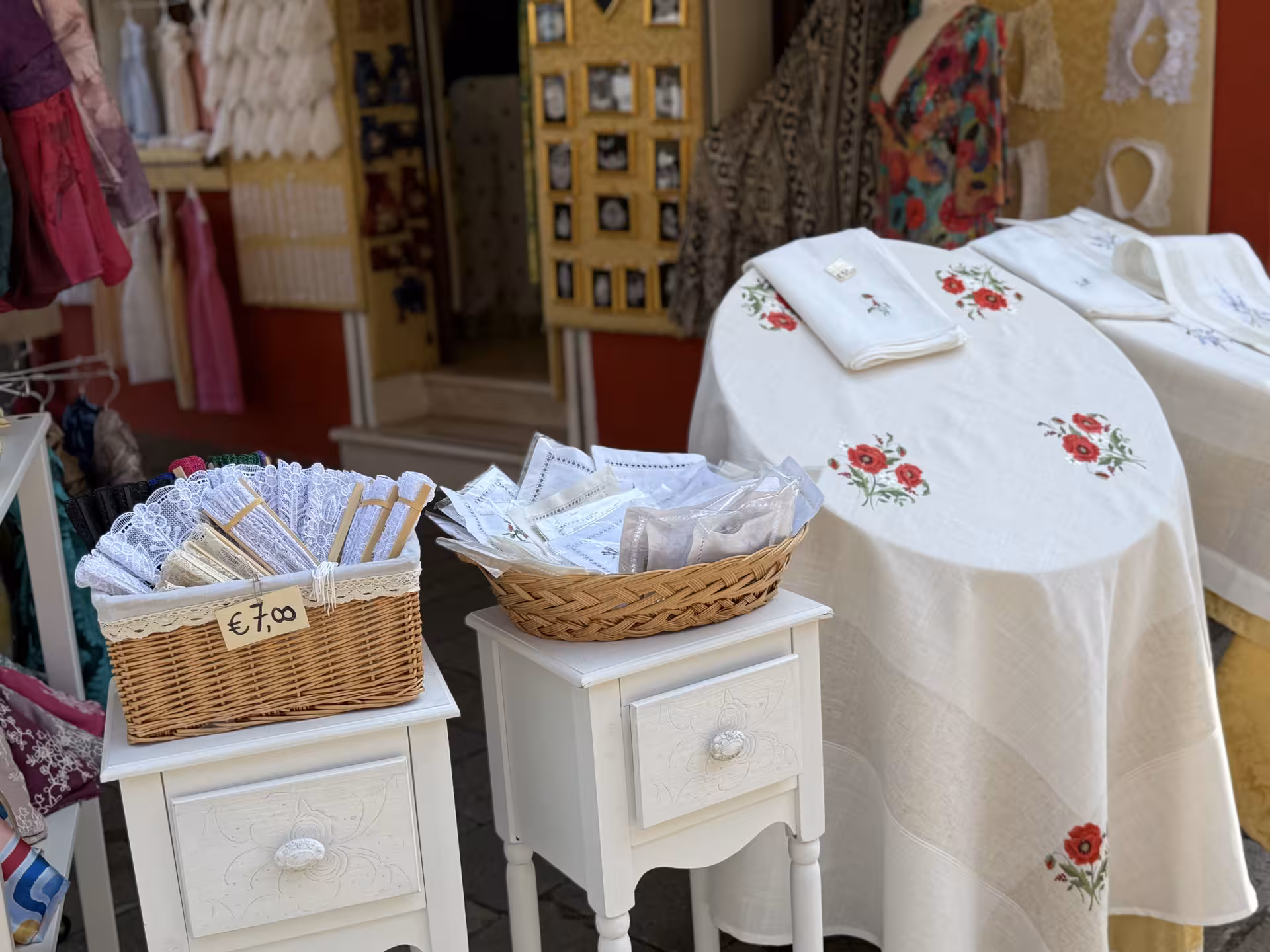 Charming Burano lace shop displaying intricate lacework and embroidered linens, a highlight of the guided island tour.