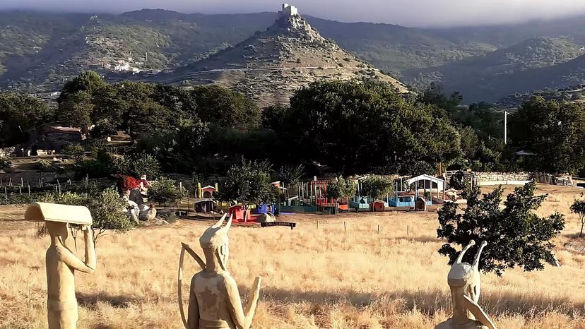 Scenic view of Burgos farm with statues, lush greenery, and mountain backdrop, ideal for a unique tasting experience.