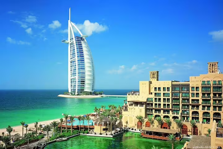 Iconic Burj Al Arab hotel beside turquoise waters, viewed from the Madinat Jumeirah during a Dubai sightseeing tour.