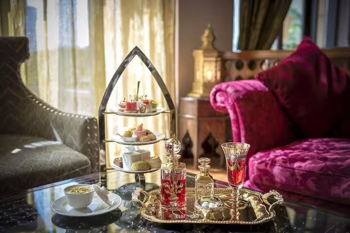 Elegant afternoon tea at Al Bayt lounge with Arabic decor, tiered pastries, and traditional drinks on a golden tray in Dubai