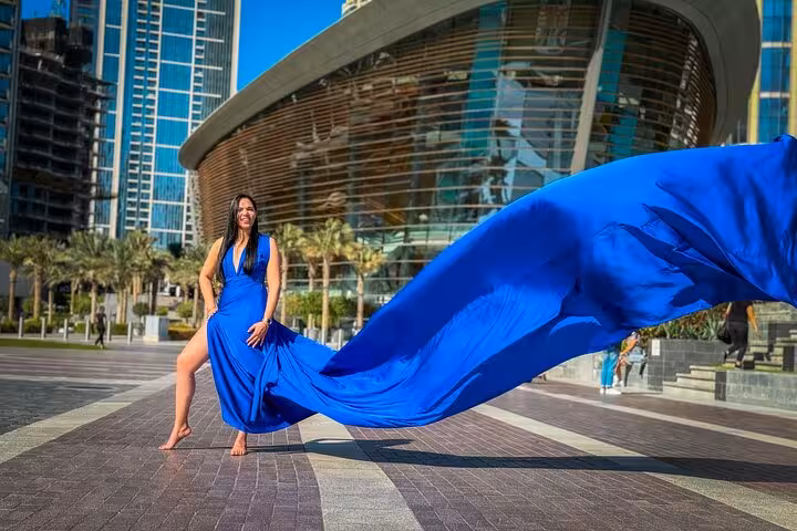 Woman in elegant blue dress posing near iconic Burj Khalifa for a stunning Instagram flying dress shoot.