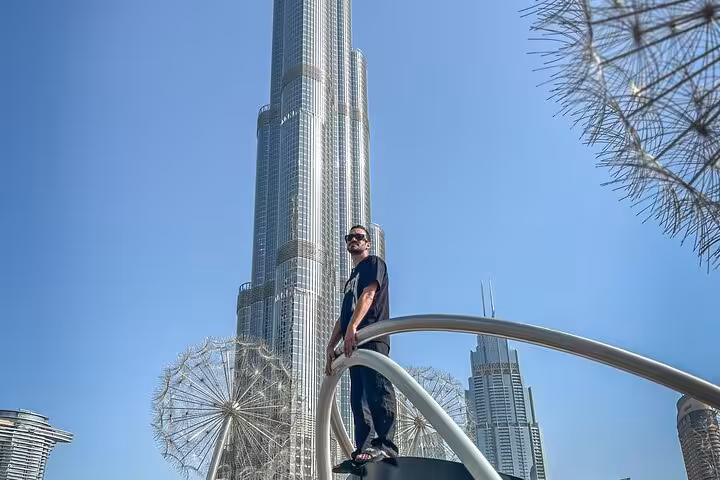 Traveler poses on a bridge with the Burj Khalifa towering in the background during a Dubai Instagram tour.