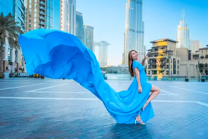 Model in a dramatic blue dress elegantly poses near the Burj Khalifa for a memorable flying dress photography experience.