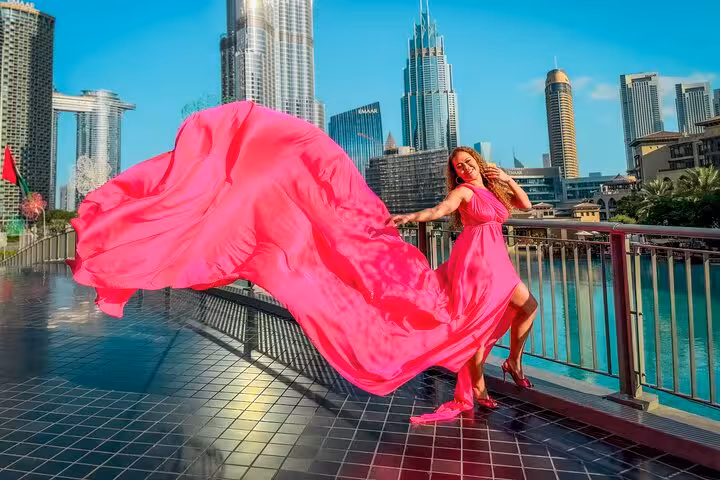 Woman in vibrant pink dress poses with Burj Khalifa skyline for Instagram videography in Dubai.