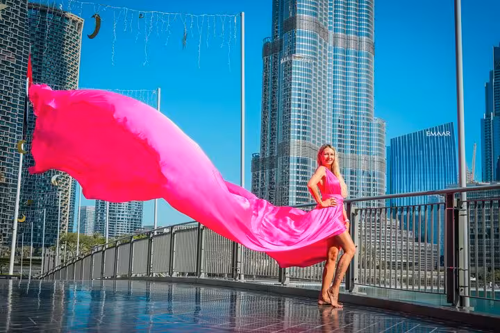Model in a vibrant pink dress with long train stands before Burj Khalifa, capturing a stunning Instagram moment.