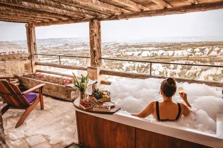 Traveler relaxing in a terrace hot tub overlooking Cappadocia valleys on a business class plane day tour