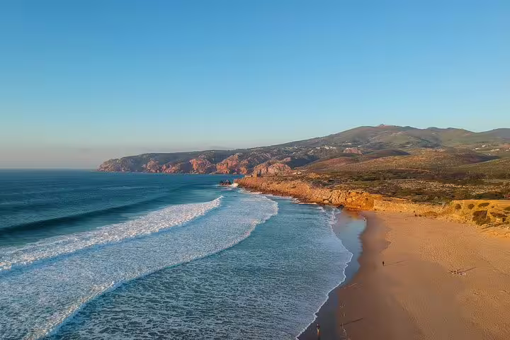 Scenic view of a sunlit beach and rugged coastline at Cabo da Roca, part of the Sintra and Cascais day tour in Portugal.