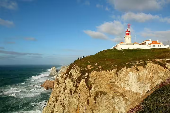 Scenic view of Cabo da Roca lighthouse atop rugged cliffs overlooking the Atlantic Ocean on a Sintra and Cascais private tour.