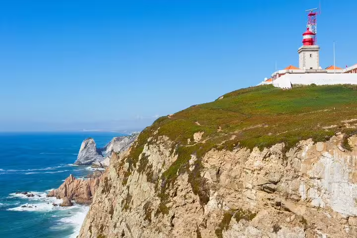Scenic view of Cabo da Roca lighthouse perched on rugged cliffs overlooking the Atlantic Ocean, a highlight of the Sintra day tour.