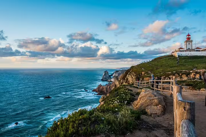 Scenic view of Cabo da Roca's dramatic cliffs and lighthouse at sunset, part of the Sintra: Pena Palace, Regaleira, Roca & Cascais Day Tour.