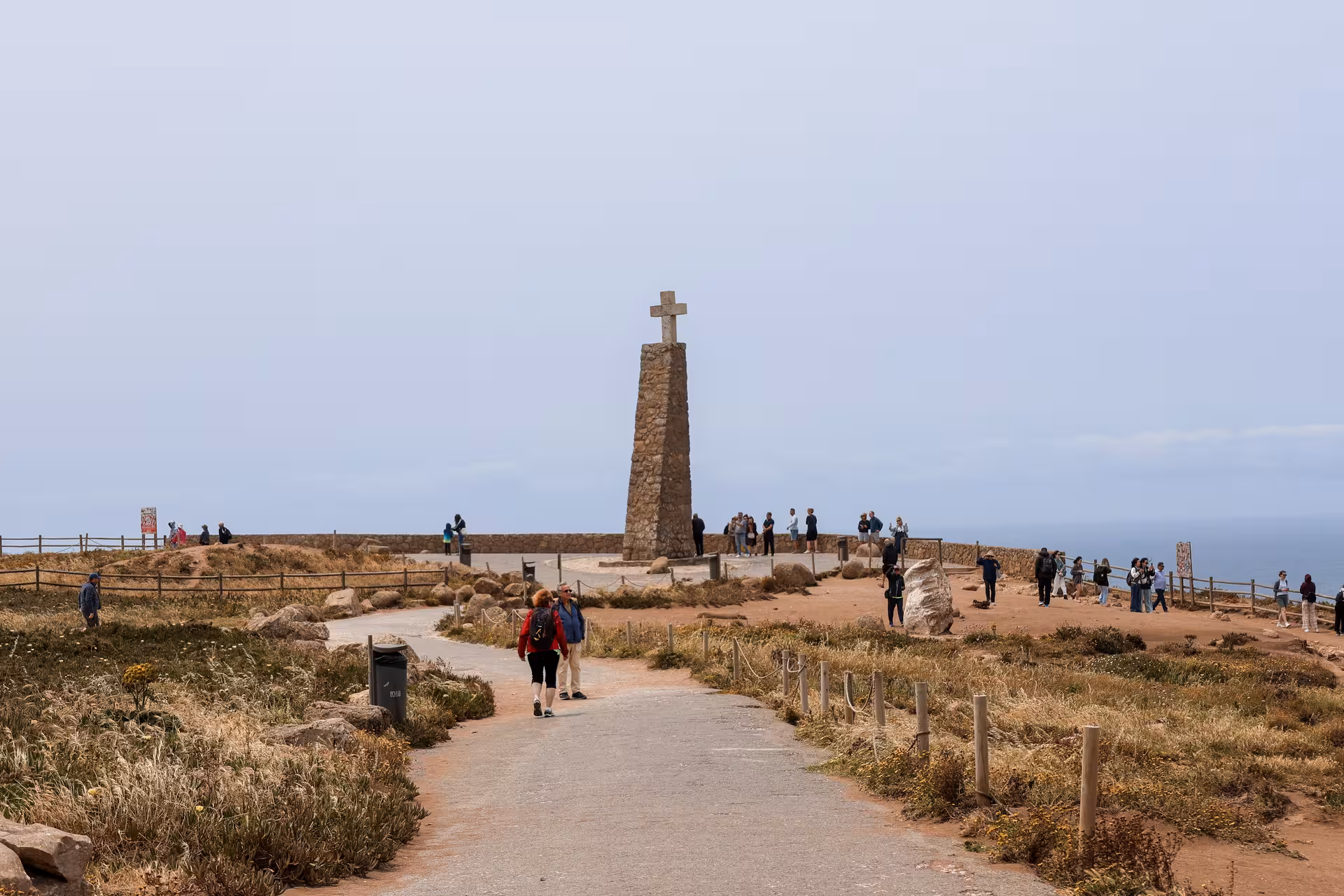 Visitors exploring Cabo da Roca, the westernmost point of mainland Europe, marked by a monumental stone cross.
