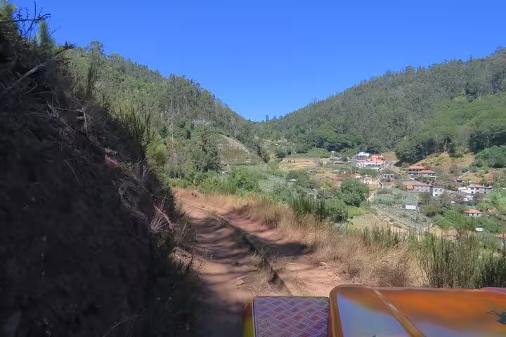 Off-road 4WD adventure through lush mountain trails near Cabo Girão, showcasing scenic landscapes and distant villages.