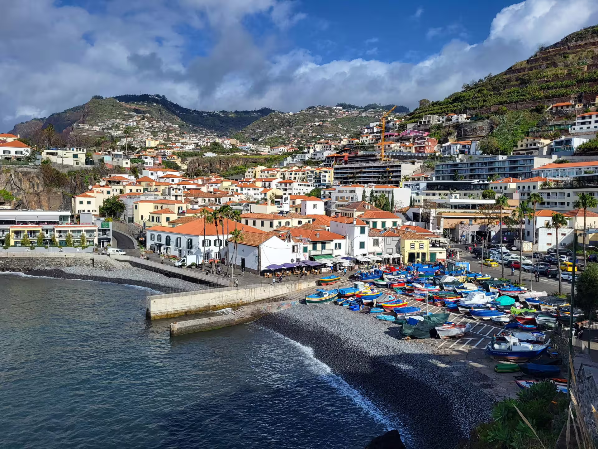 Coastal village with colorful boats and hillside houses in Madeira, perfect for Cabo Girão and Seixal day tour exploration.