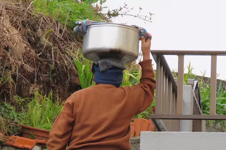 Person carrying a large pot on their head, showcasing traditional lifestyle during the Cabo Girão Skywalk and 4x4 Adventure tour.