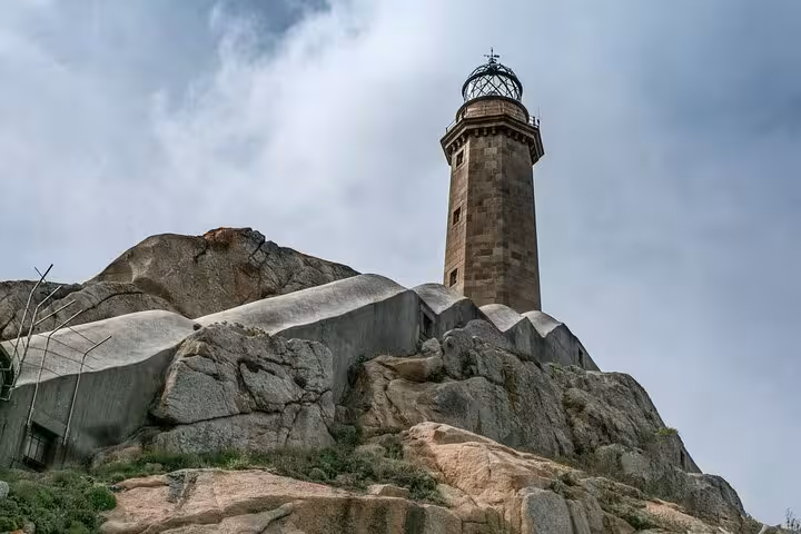 Historic Cabo Vilan lighthouse atop rugged cliffs under a cloudy sky, part of the Finisterre, Muxia, and Cabo Vilan excursion.