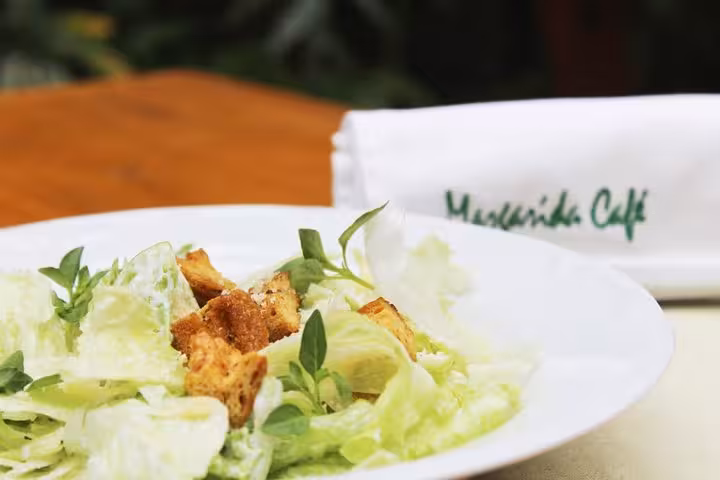 Fresh Caesar salad with crisp lettuce, croutons, and herbs served at a traditional Brazilian diner with live music.