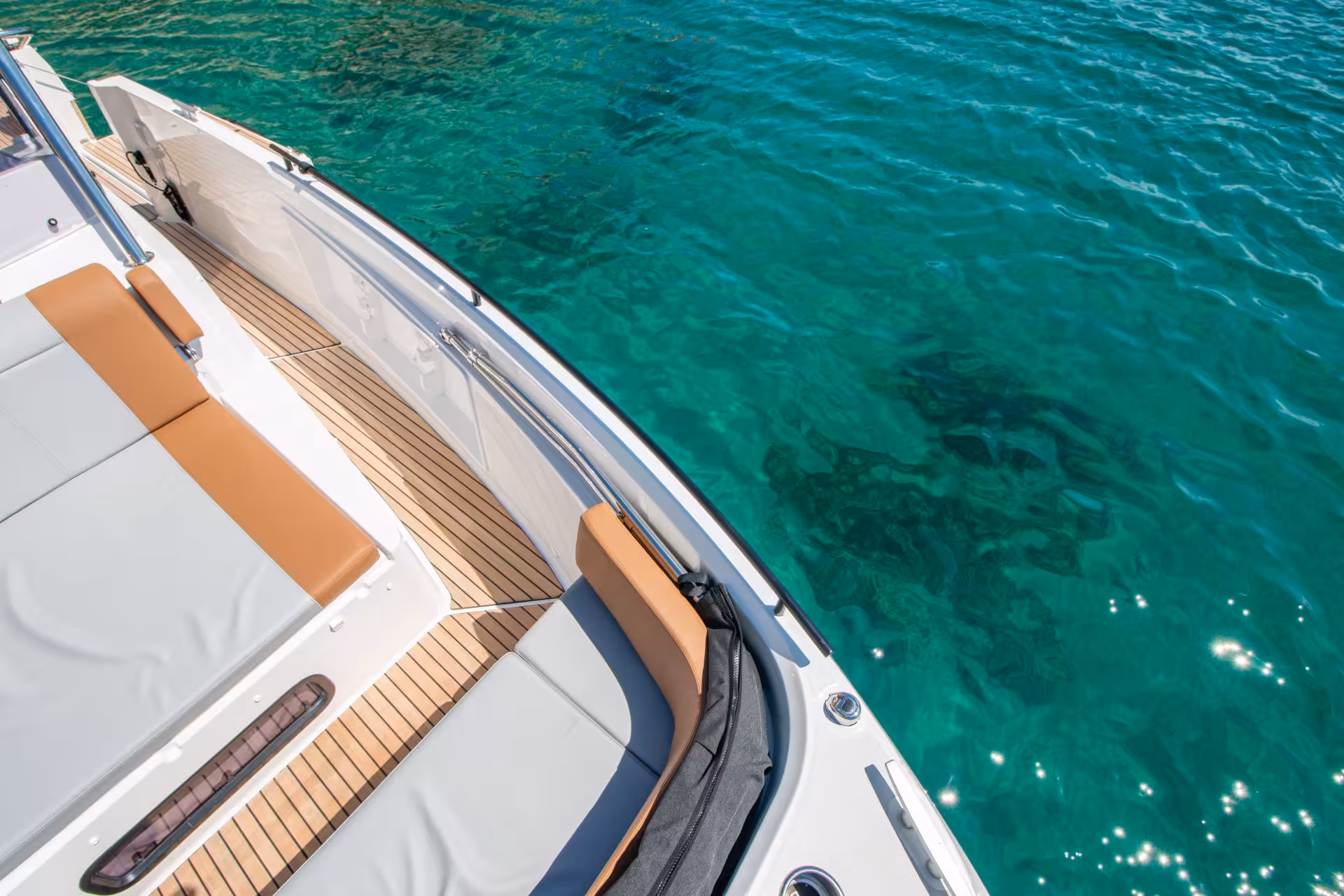 Close-up of a sleek boat deck with seating, surrounded by Cagliari's crystal-clear emerald waters.