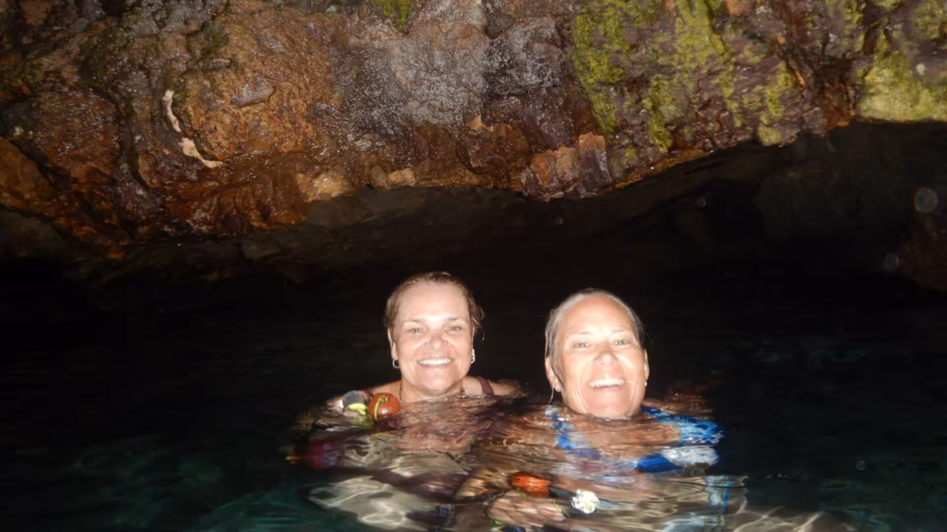 Two people enjoying snorkeling in a cave with shimmering water during a Cagliari boat tour adventure.