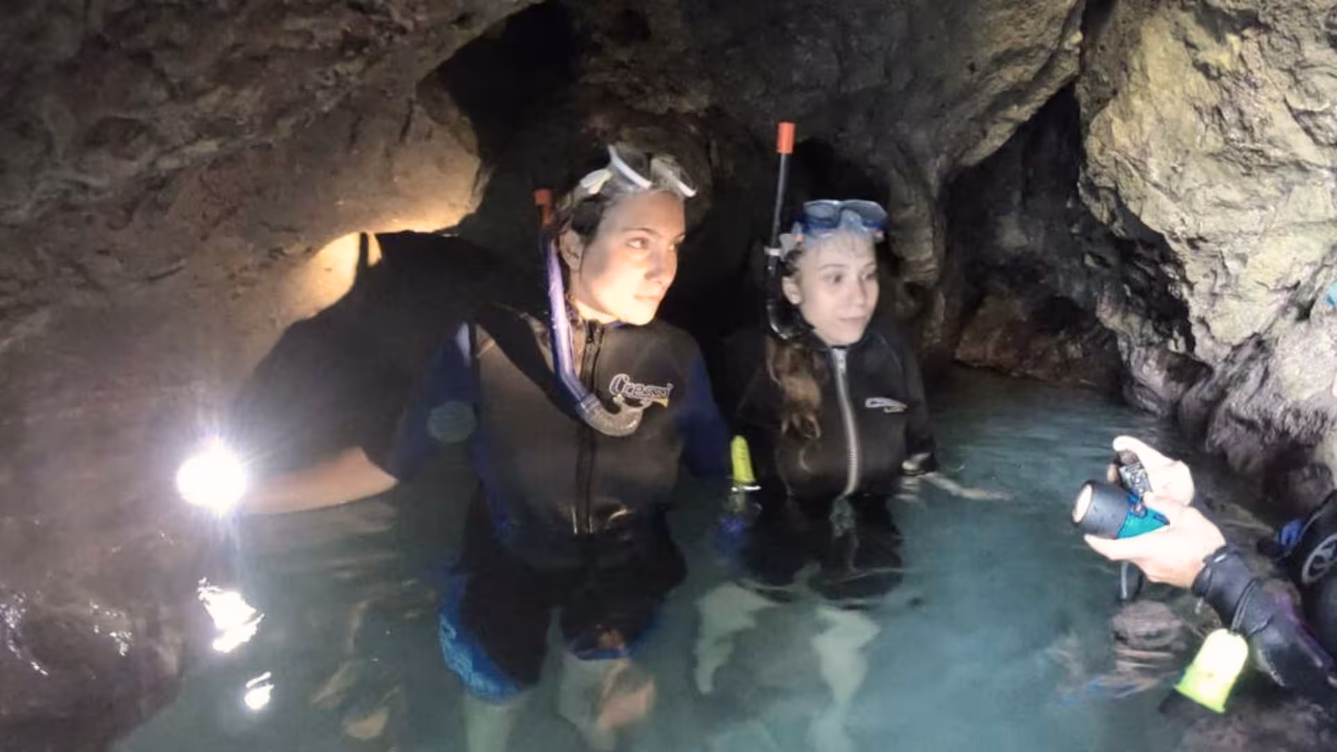 Two snorkelers explore a stunning cave during a Cagliari boat tour with snorkeling adventure.