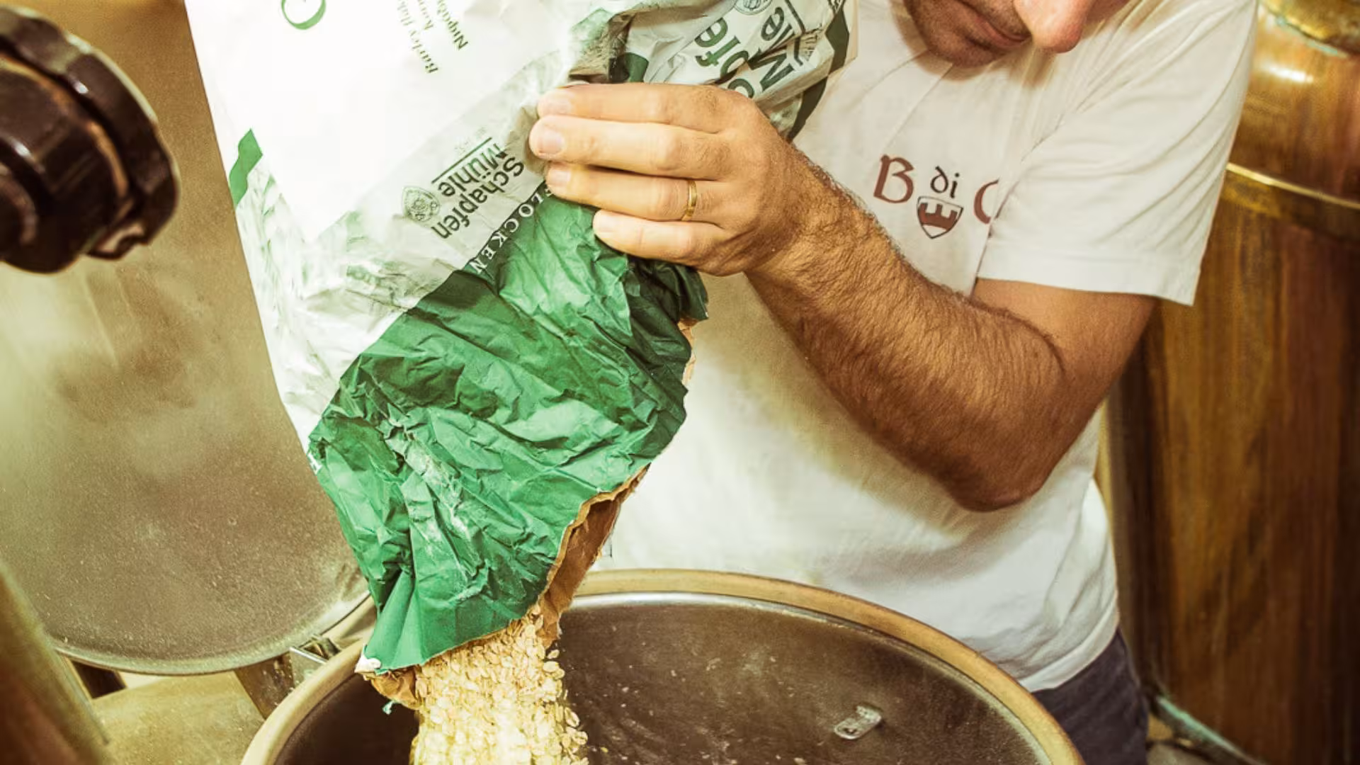 Brewery worker adding malt to a brewing vat during a hands-on tour in Cagliari, demonstrating beer production steps.