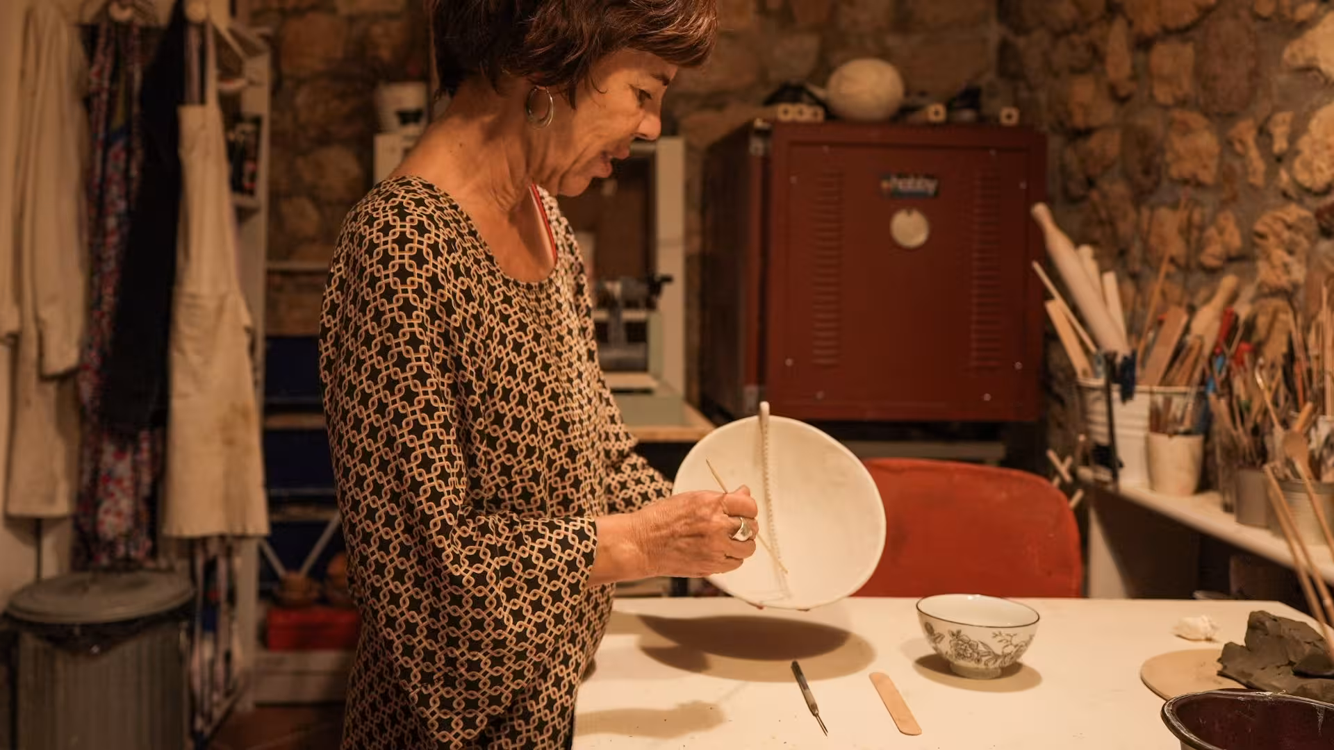 Instructor demonstrating ceramic techniques on a plate at a Cagliari pottery workshop.