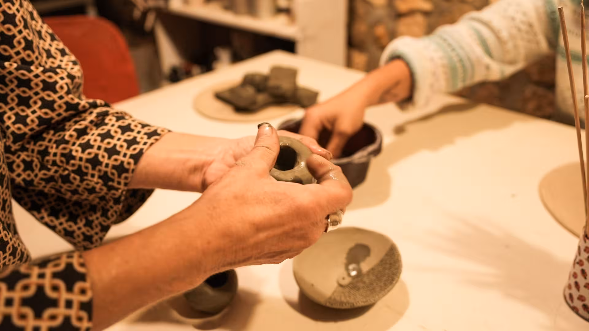Close-up of hands molding clay into pottery at a Cagliari ceramics workshop, highlighting creative craftsmanship.