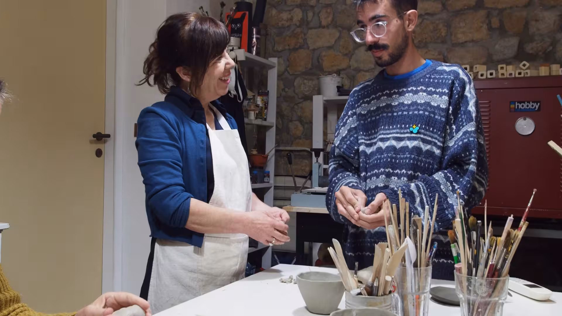 Instructor and participant engaging in hands-on learning at a Cagliari ceramics workshop.