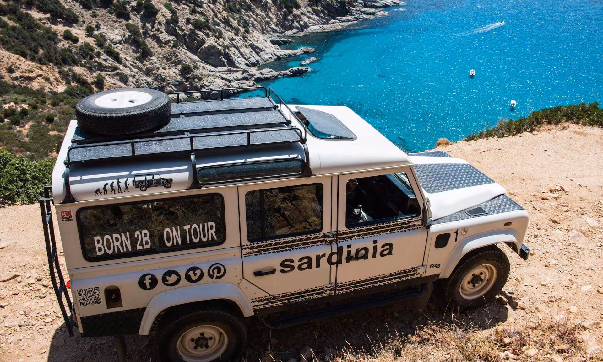 Jeep parked on a cliffside during a Cagliari to Chia tour, offering breathtaking views of Sardinia's turquoise waters.